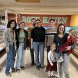 Six adults and two children posing in front of bowling lanes